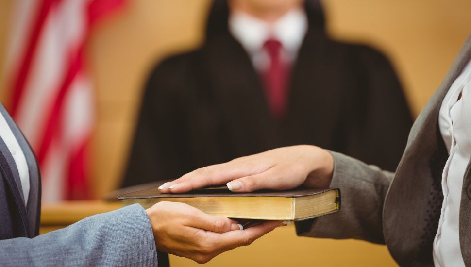 Person being sworn in with hand on book.