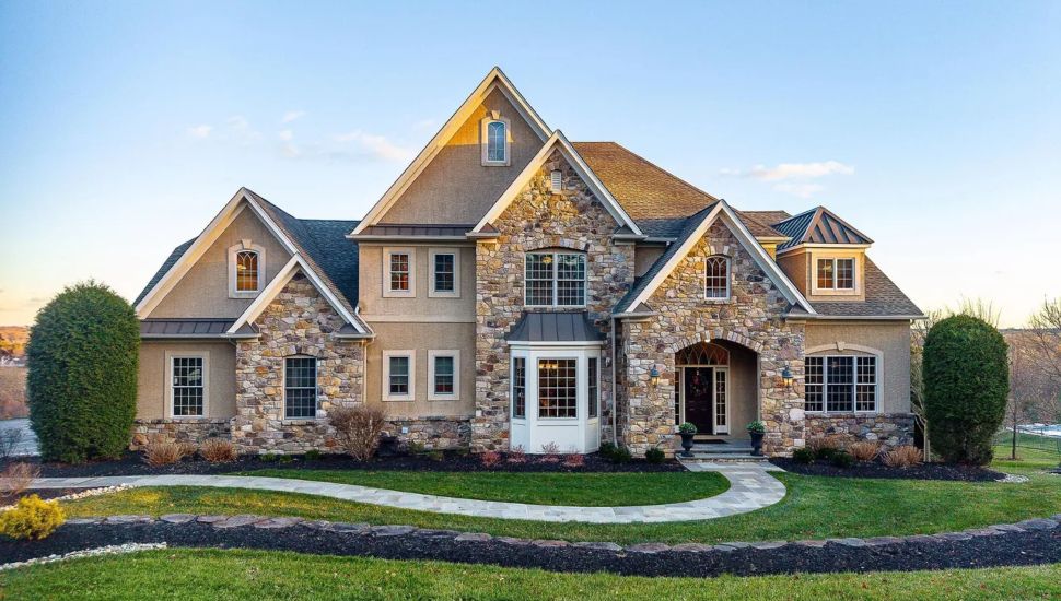 Stone house with a walkway framed by two trees.