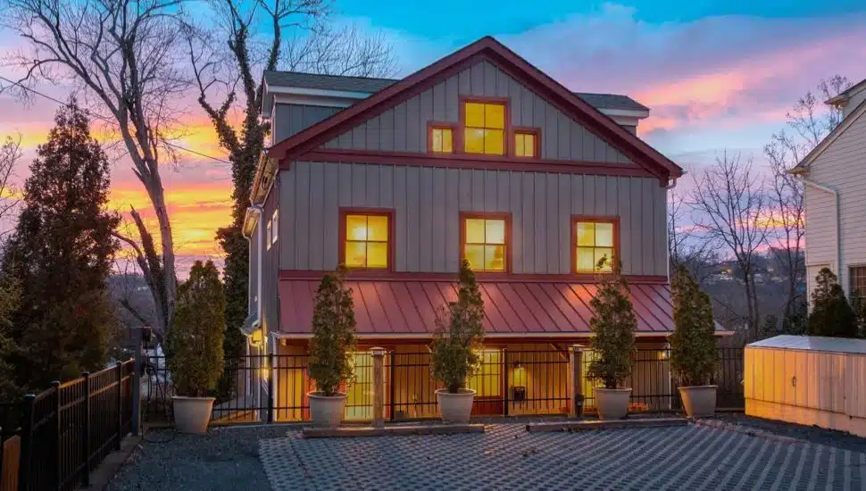 Gray house with red roofing at sunset.
