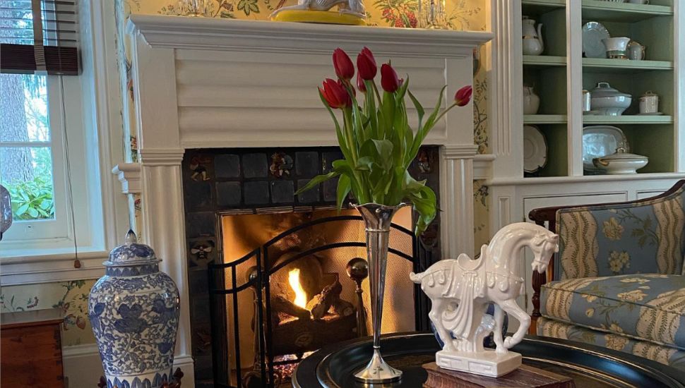 Horse statue and flowers on a table in front of a fireplace.