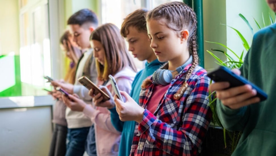 Middle school kids looking at their phones.