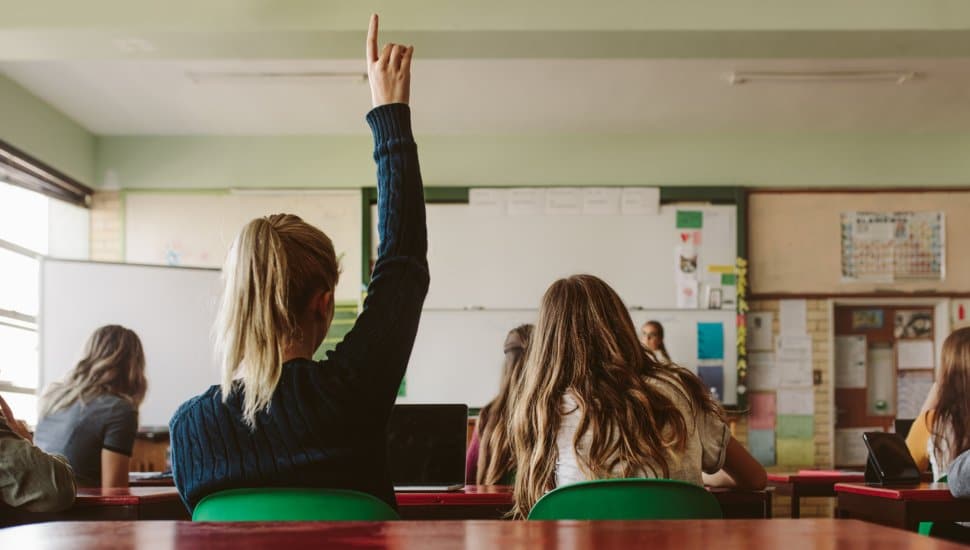 Student raising hand in classroom.