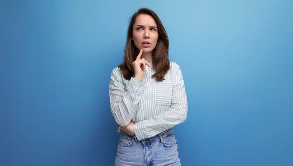 thoughtful 25 year old brown-haired female person dressed in a striped blouse.