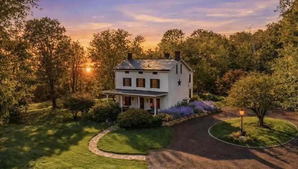 White farmhouse at sunset surrounded by trees and planted lavender.