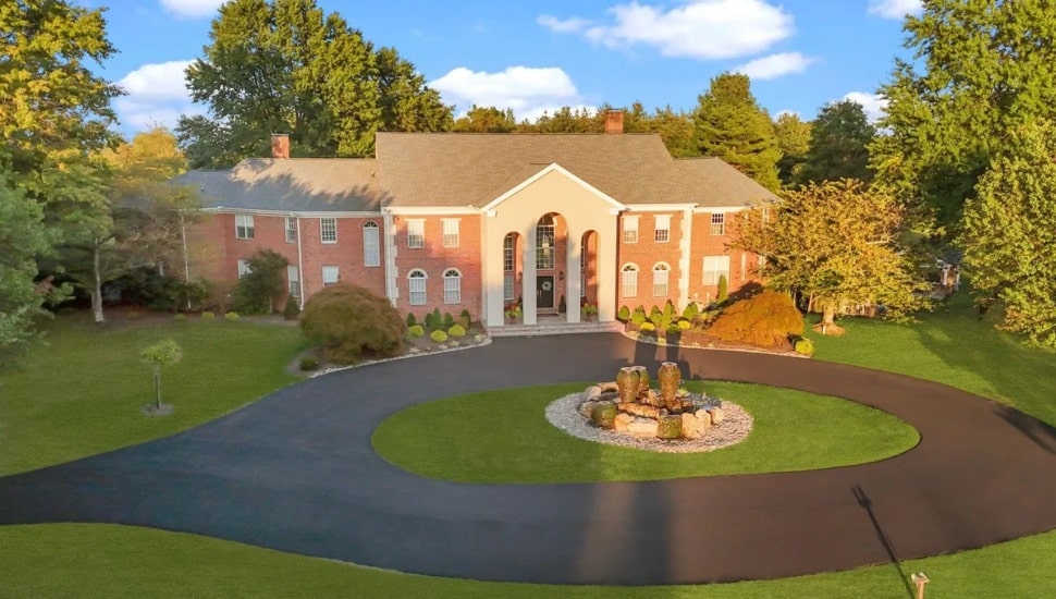 Georgian-style brick manor with stone columns and a roundabout driveway.