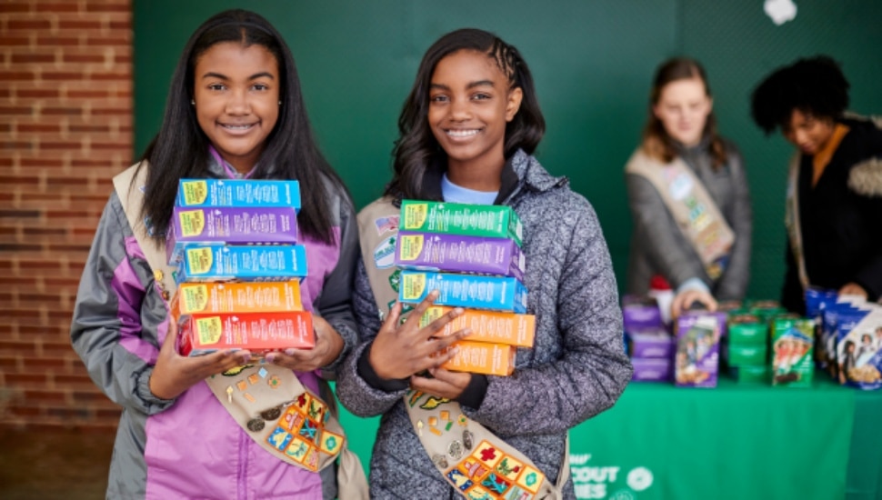 Girl Scouts selling boxes of cookies.
