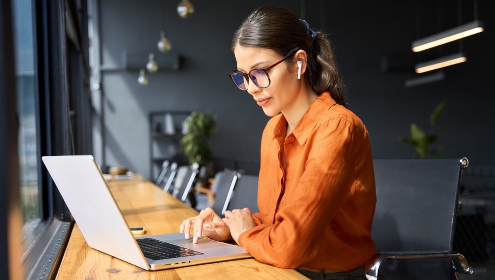 Businesswoman working on laptop computer sitting at office.