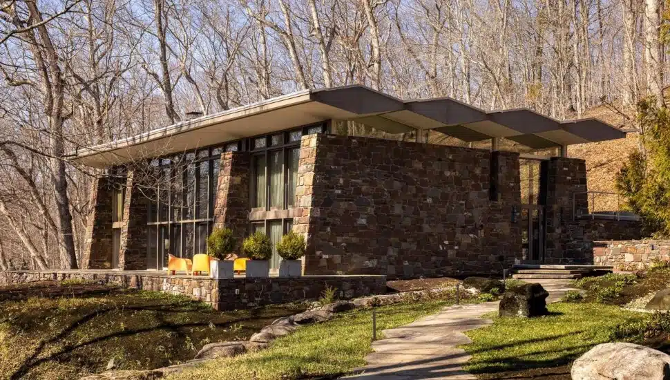 Modern home with stone exterior surrounded by trees.