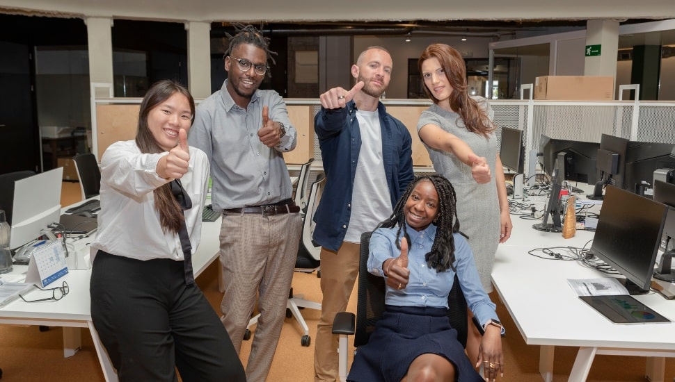 A group of happy employees give a thumbs up.