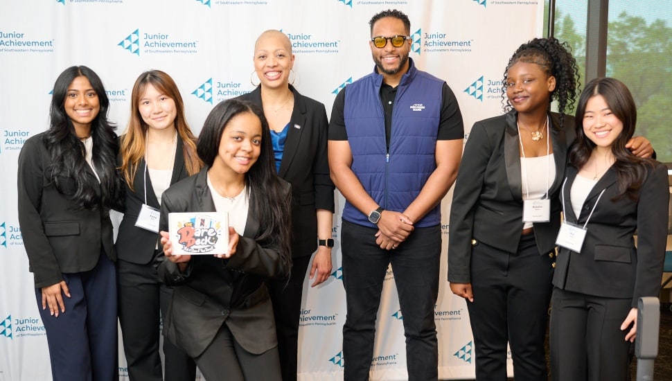 Student entrepreneurs pose for group picture with sponsoring bank executive.