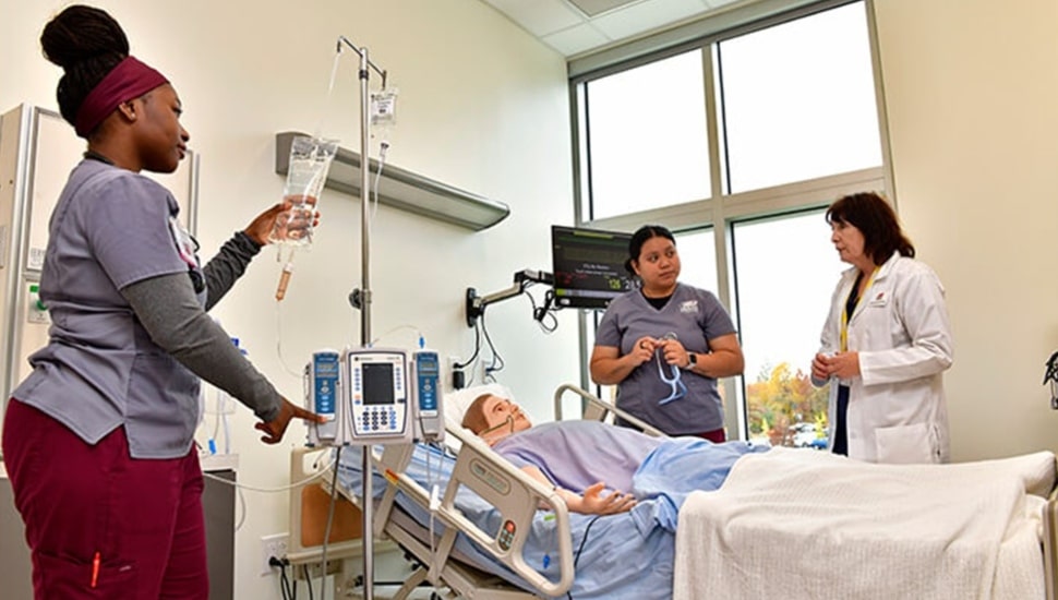 Student nurses care for mannequin patient.