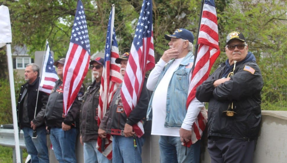 Individuals with American flags gathered at bridge dedication ceremony.