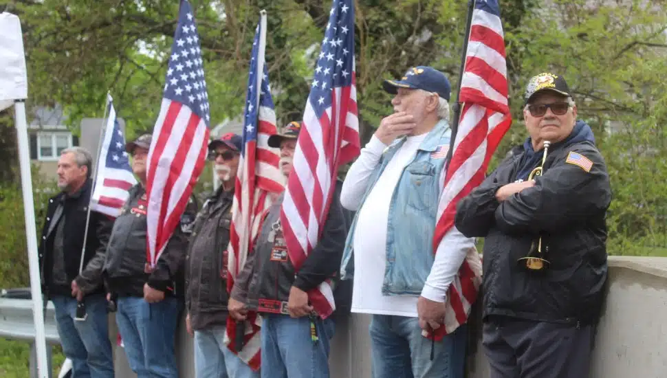 Individuals with American flags gathered at bridge dedication ceremony.