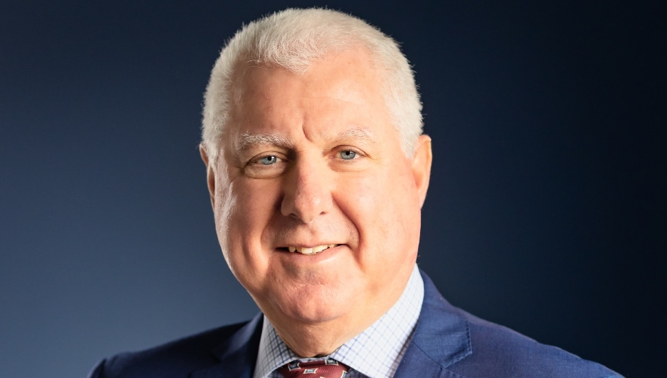 Headshot of older banking executive in blue suit.