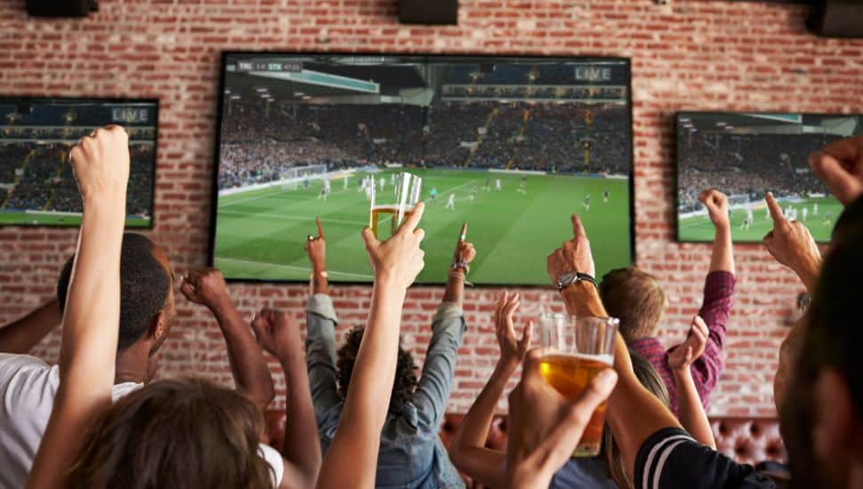 People cheering at a sports bar as they watch a game on tv.