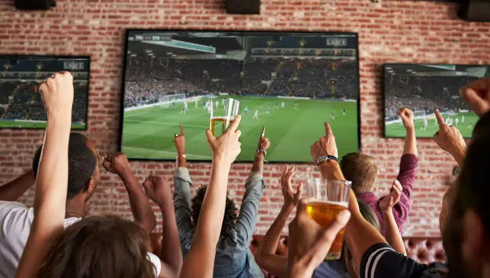 People cheering at a sports bar as they watch a game on tv.