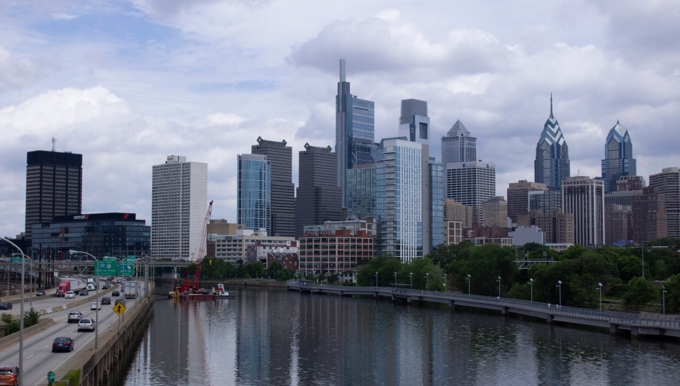 A wide shot of the Philadelphia skyline through the tree lines.
