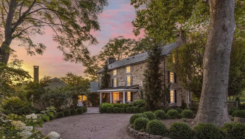 Stone cottage surrounded by trees at sunset.