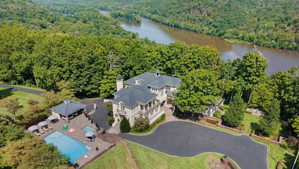 Cliffside Mansion Summer Escape in Tinicum Township sits high above the Delaware River on 12 gated acres, with a resort-sized pool, covered cabana, and sweeping river views that set the tone the moment you arrive.