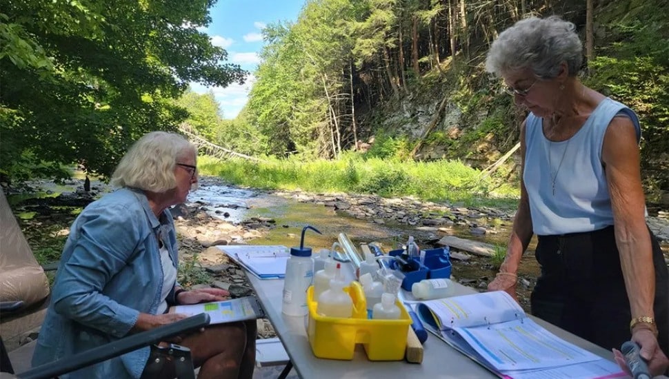 Two Volunteers test water quality along a local stream.