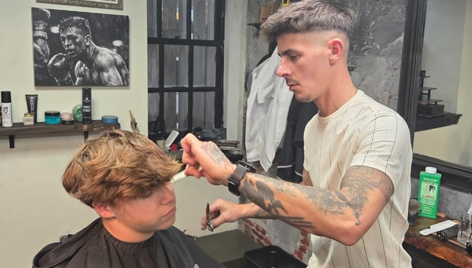 A barber cuts a young man's hair at The Way Barber Co