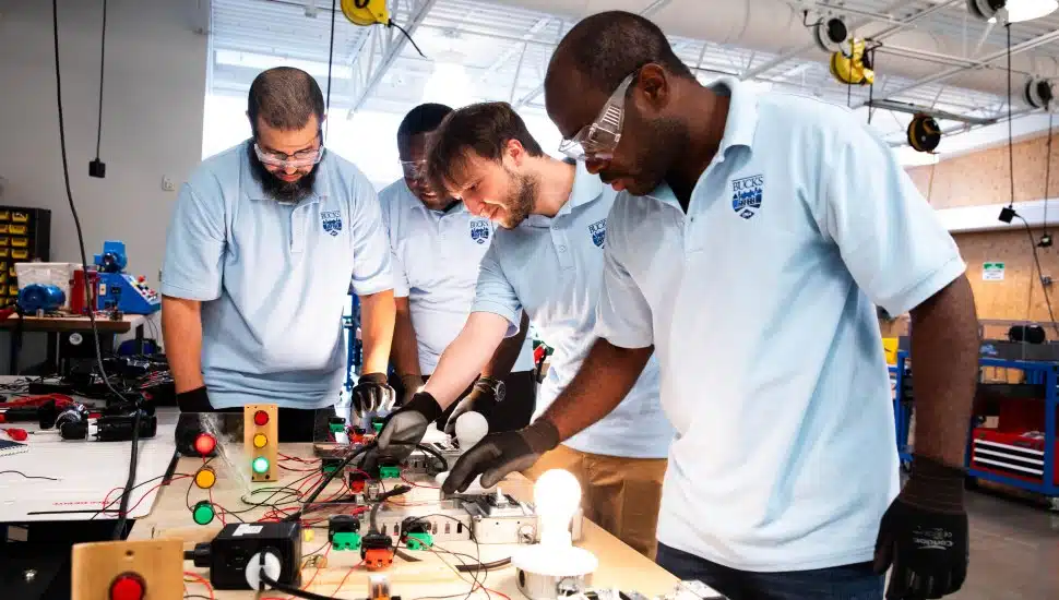 Four Bucks County Community College students work together on an electrical training exercise, part of several free workforce development programs preparing county residents for high-demand careers in the trades, manufacturing, and beyond.
