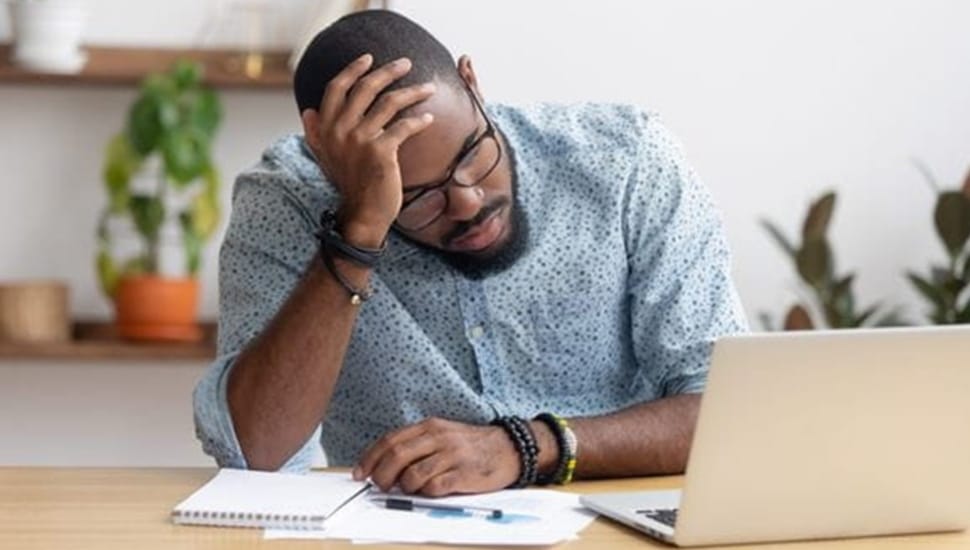 Man sits in frustration at his laptop computer.
