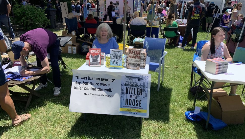 Author Kathryn Canavan at an outdoor book event, signing copies of Killer in the House and True Crime Philadelphia.