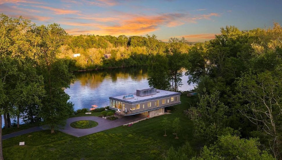 The glass-front estate at 2710 River Road in New Hope sits perched above the Delaware River, framed by eight acres of scenic nature.